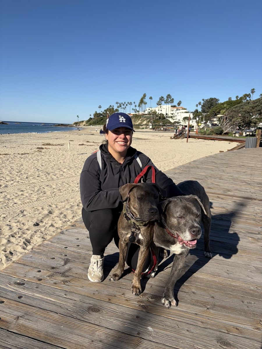 Candace on a sunny beach boardwalk with two happy dogs