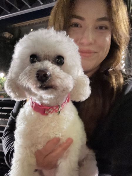 A curly white pup cuddled up with Candace